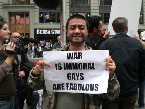 A man with a sign that says "War is Immoral Gays are fabulous"
