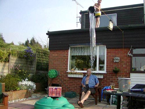 Boy Pouring Bucket Of Water On Grandpa